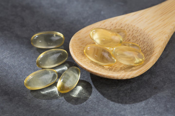Cod Liver Oil Capsules on wooden spoon