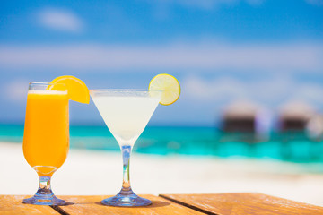 glass of fruit cocktail and sunglasses by the beach