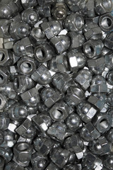 Lots of galvanized industrial steel cap nuts on a white background