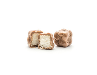 Sliced milk chocolate cube with coconut inside and one whole isolated on white background.