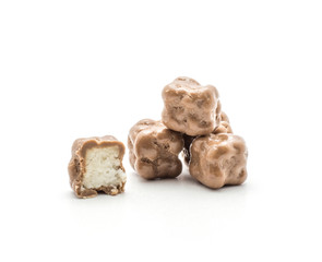 Milk chocolate cubes and one sliced half with coconut inside isolated on white background.