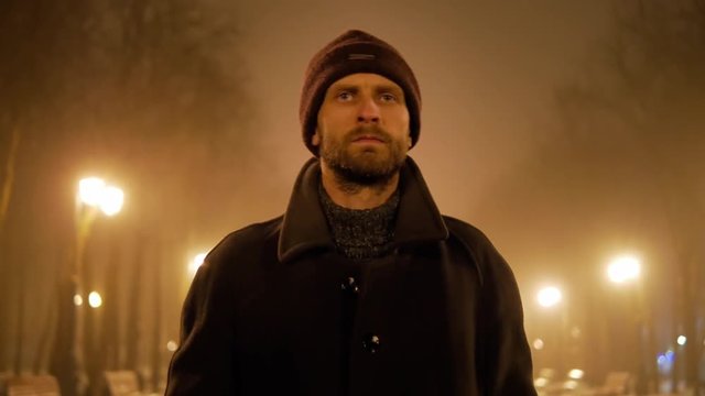 4k Bearded brutal criminal look man walks at foggy night city and searching for some one