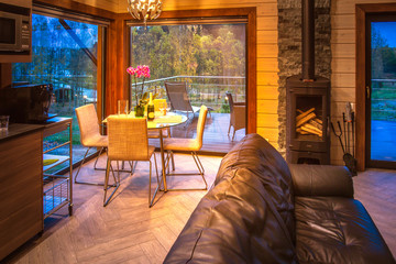Living room of a country house. Living room with large windows. A wooden house with a fireplace. Cottage with a fireplace. Fireplace by the window.