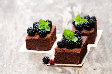 Chocolate  brownie pieces with blackberries on wooden table