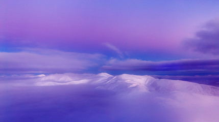 Amazing pink toned winter scenery of snow caped peaks in mountain ridge Chornohora in Ukraine.