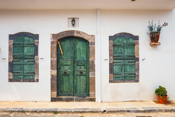 green shutters and doors on a white wall, close up