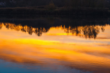 Fototapeta premium tree silhouettes reflected in the mirror during sunset