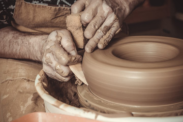 elderly man making pot using pottery wheel in studio