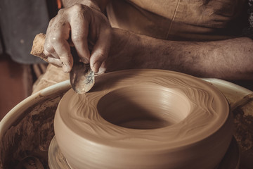 elderly man making pot using pottery wheel in studio