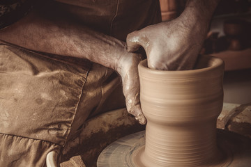 elderly man making pot using pottery wheel in studio