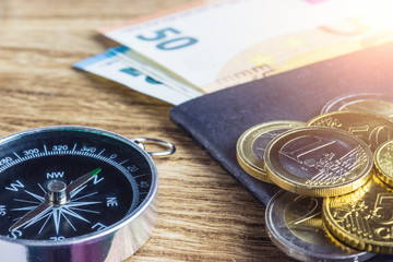 Money euros banknotes ,compass and passport on wooden background