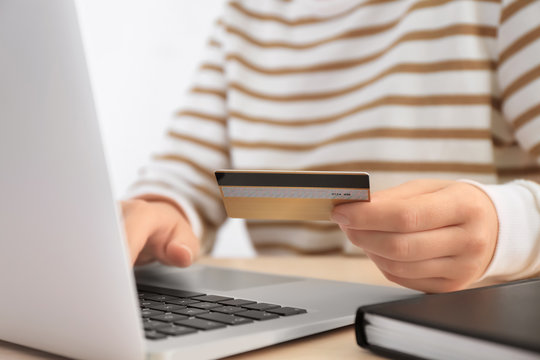 Woman with credit card and laptop at table, closeup. Internet shopping concept