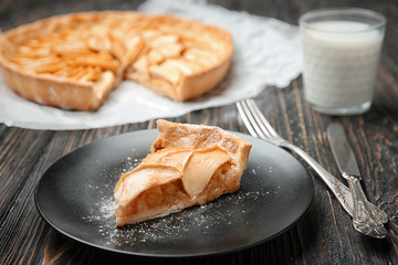 Plate with piece of tasty apple tart on wooden table