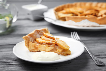Plate with piece of tasty apple tart on wooden table