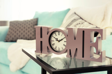 Table with elegant clock near mint couch in living room