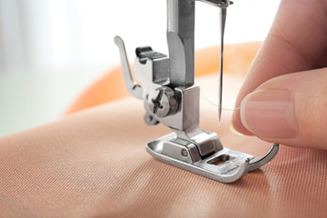 Woman using sewing machine, closeup