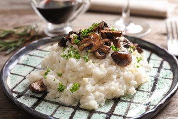 Plate with delicious risotto and mushrooms on table
