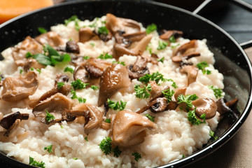 Dish with risotto and mushrooms on table, closeup
