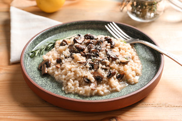 Plate with delicious risotto and mushrooms on table