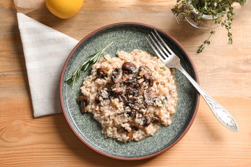 Plate with delicious risotto and mushrooms on table