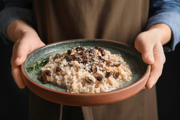 Woman holding plate with delicious risotto and mushrooms, closeup