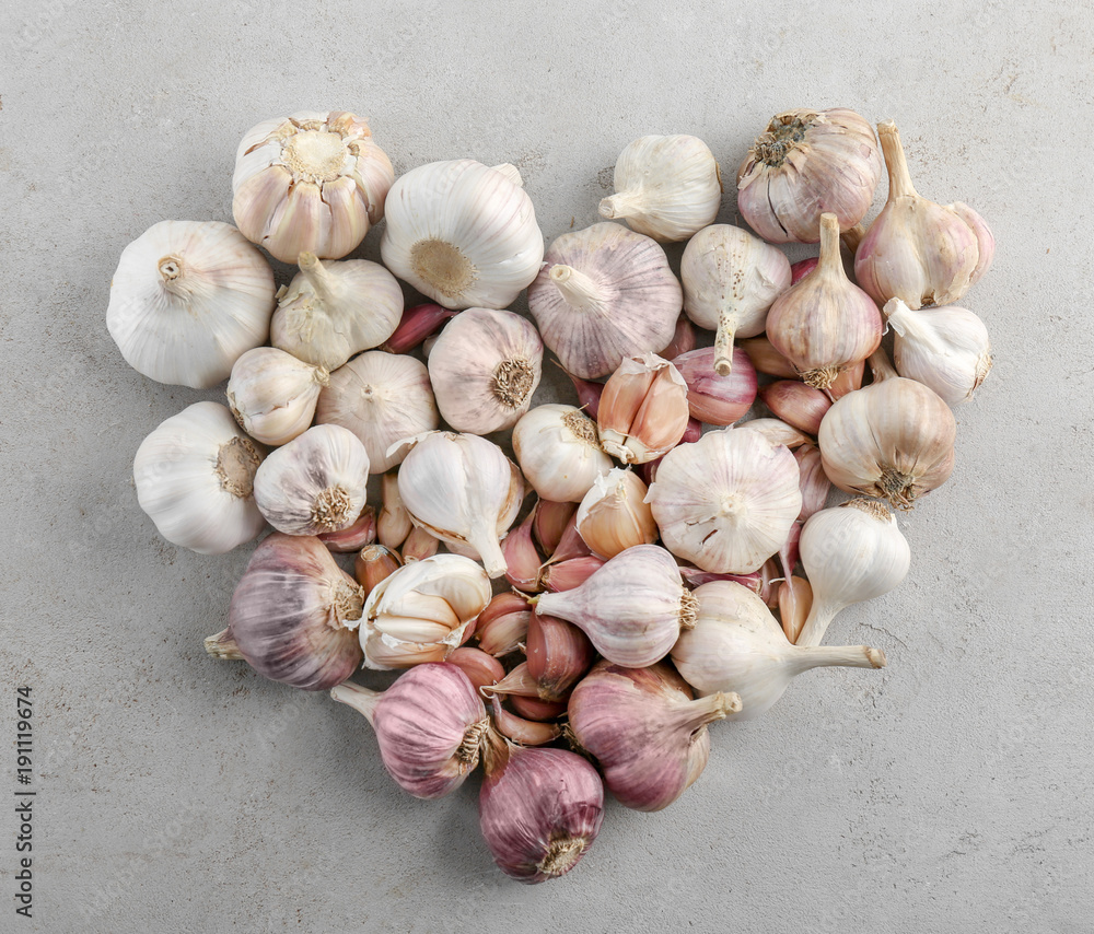 Wall mural Heart shape of fresh garlic heads on grey background