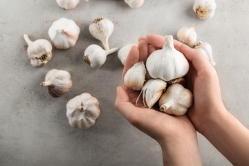 Woman holding fresh garlic on grey background