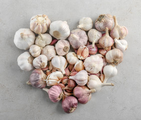 Heart shape of fresh garlic heads on grey background