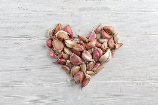 Heart shape of fresh garlic on white wooden background