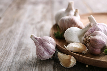 Plate with fresh garlic on wooden table