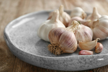 Plate with fresh garlic on table