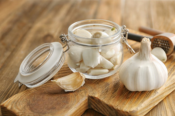 Jar with garlic cloves and head on board