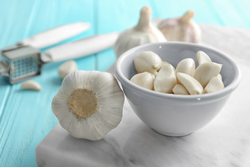 Bowl with garlic cloves and head on board