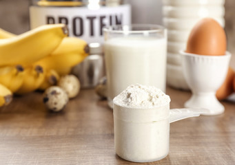 Scoop with protein powder and products on table