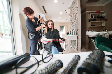 Hairdresser dries hair with a hairdryer in beauty salon