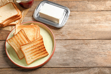Plate with tasty toasted bread on wooden table