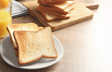 Plate with tasty toasted bread on wooden table