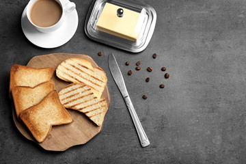 Wooden board with tasty toasted bread on table