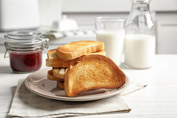 Plate with tasty toasted bread on table