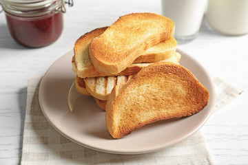 Plate with tasty toasted bread on table