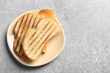 Plate with tasty toasted bread on table