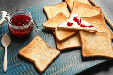 Tasty toasted bread with jam on wooden board