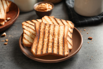 Plate with tasty toasted bread on table