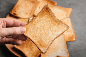 Woman holding tasty toasted bread over table, closeup