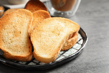 Plate with tasty toasted bread on table
