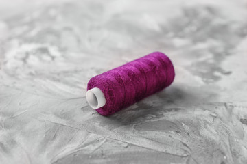 Fototapeta na wymiar Spool of sewing thread on grey background
