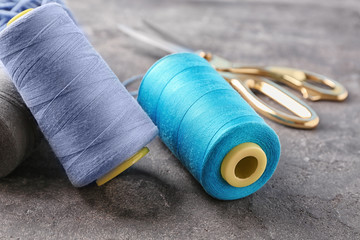 Colorful sewing threads on grey background, closeup