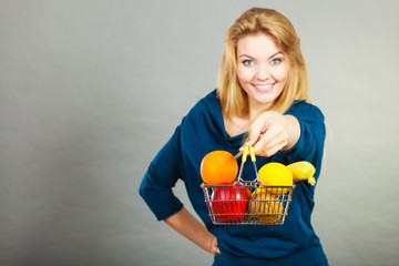 Woman holding shopping basket with fruits inside