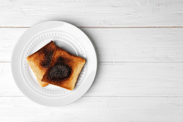 Plate with burnt toasted bread on light background