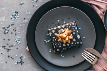 Festive party table setting with plate, fork, knife, and gift box.